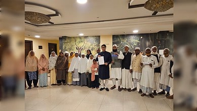 Pilgrims standing together in a hotel lobby holding flight papers.