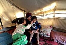 A woman sits with children in Gaza camp