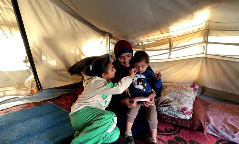 A woman sits with children in Gaza camp