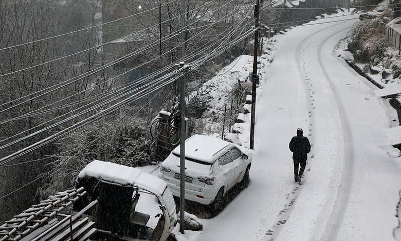 A man walks through snow amid fresh snowfall at Bhaderwah, in Doda district, Jammu and Kashmir