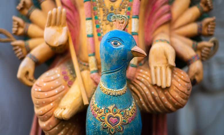 Wooden statue of Hindu god Murugan riding a peacock.