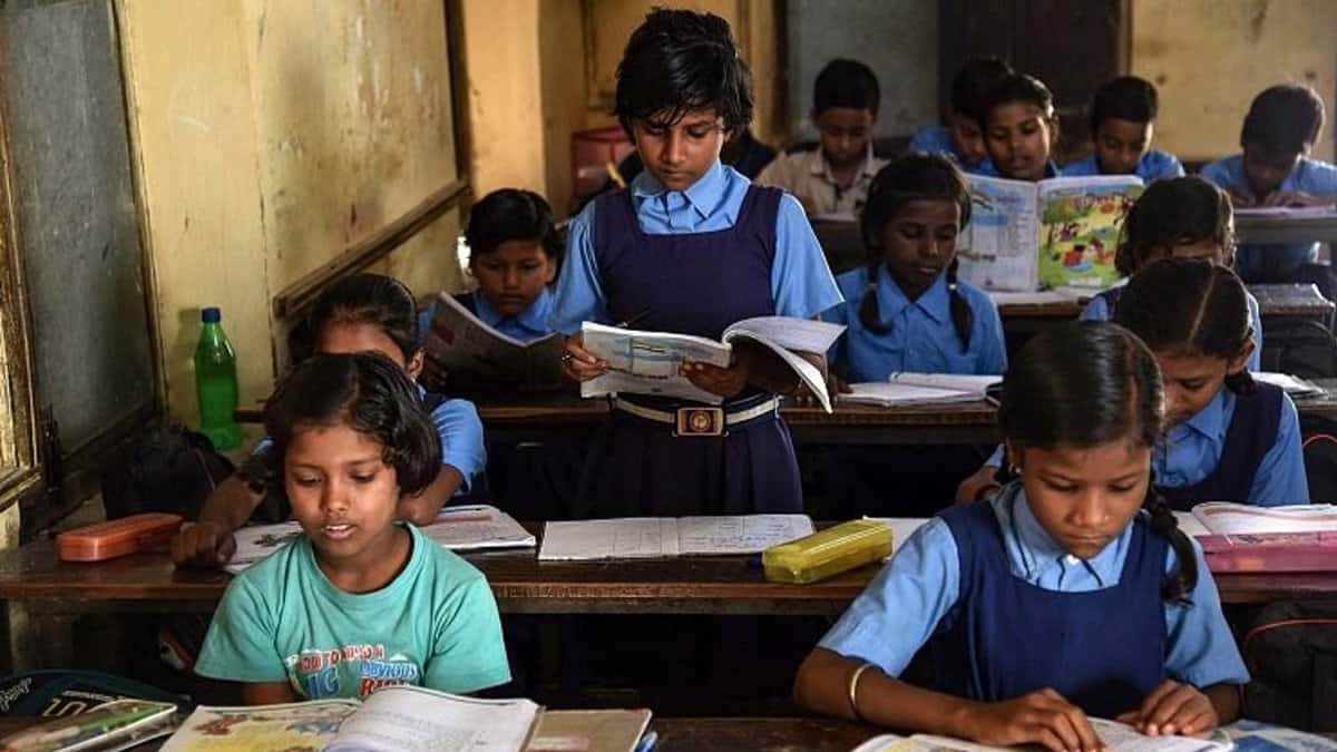 A girl reads out a passage to students; the students follow the passage line by line in the textbooks.