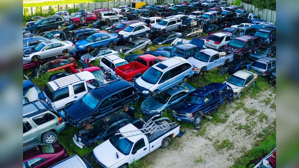 Image shows Aerial view of a densely packed salvage yard filled with various damaged and end-of-life vehicles in multiple colors.