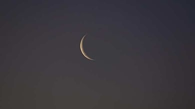 A thin crescent moon visible against a dark evening sky, marking the lunar phase used for Islamic month observations.