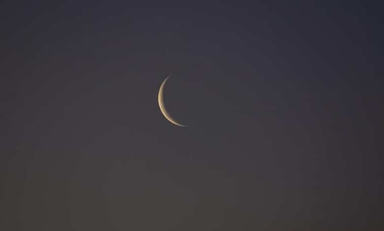 A thin crescent moon visible against a dark evening sky, marking the lunar phase used for Islamic month observations.