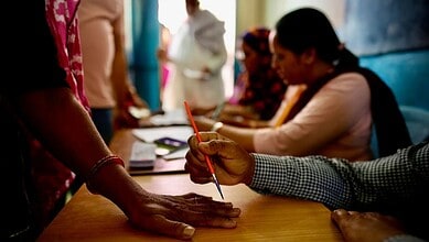 An official in Neemrana, India, paints a mark on the index finger of a woman with indelible ink before she casts her vote
