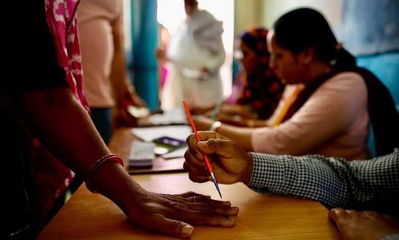 An official in Neemrana, India, paints a mark on the index finger of a woman with indelible ink before she casts her vote