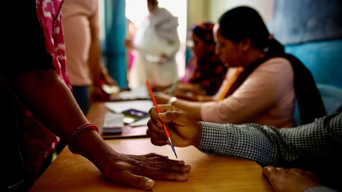An official in Neemrana, India, paints a mark on the index finger of a woman with indelible ink before she casts her vote