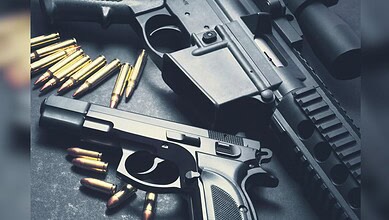 Image shows Two firearms with ammunition displayed on a dark surface.