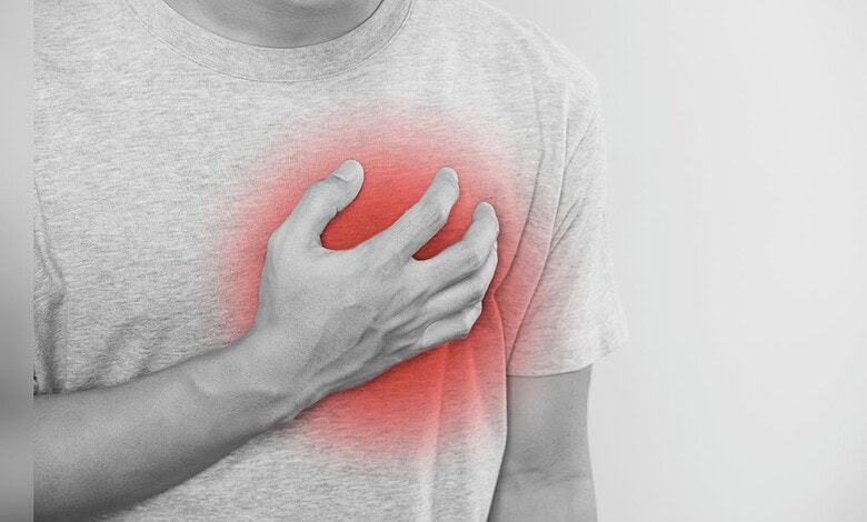 image shows A person clutching their chest with a red overlay indicating heart pain or discomfort.