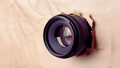 Image shows a hidden camera emerging from a cardboard wall