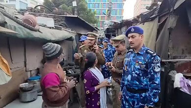 Police officers questions a family residing in a slum area during a citizenship verification drive