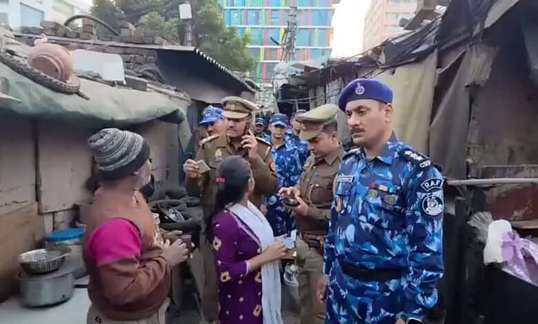 Police officers questions a family residing in a slum area during a citizenship verification drive