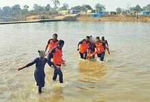 Image shows "Rescue team in orange life vests wading through water carrying people to safety