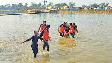 Image shows "Rescue team in orange life vests wading through water carrying people to safety