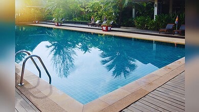 Image shows a swimming pool with trees in the background
