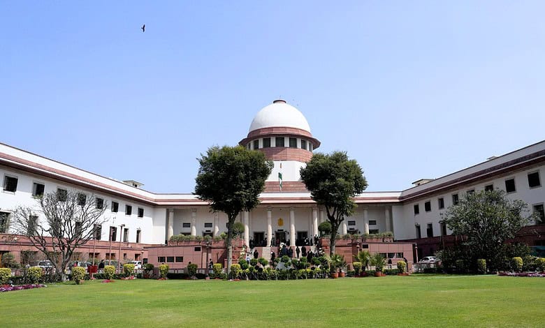 View of the Supreme Court of India with lush green lawn and trees in front.