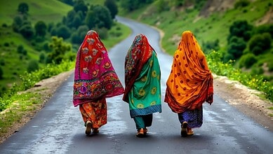 Women walking on a rural road in colourful traditional attire, green hills in the background.