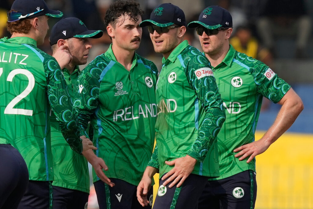 Ireland cricket team players in green uniforms discussing strategy on the field.