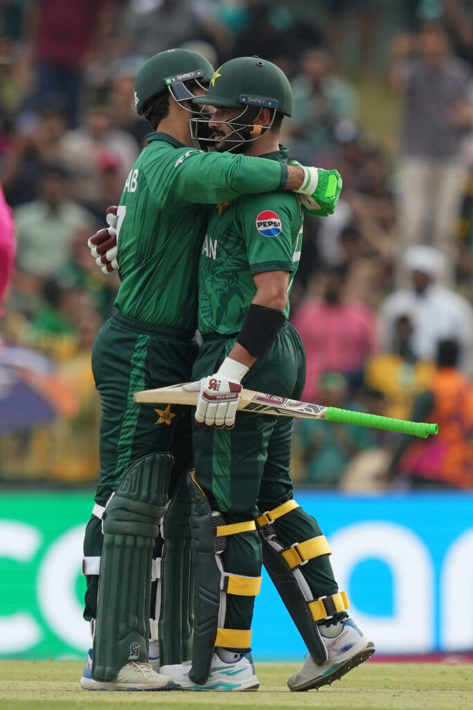 Pakistan cricket players embrace on the field after a key wicket.