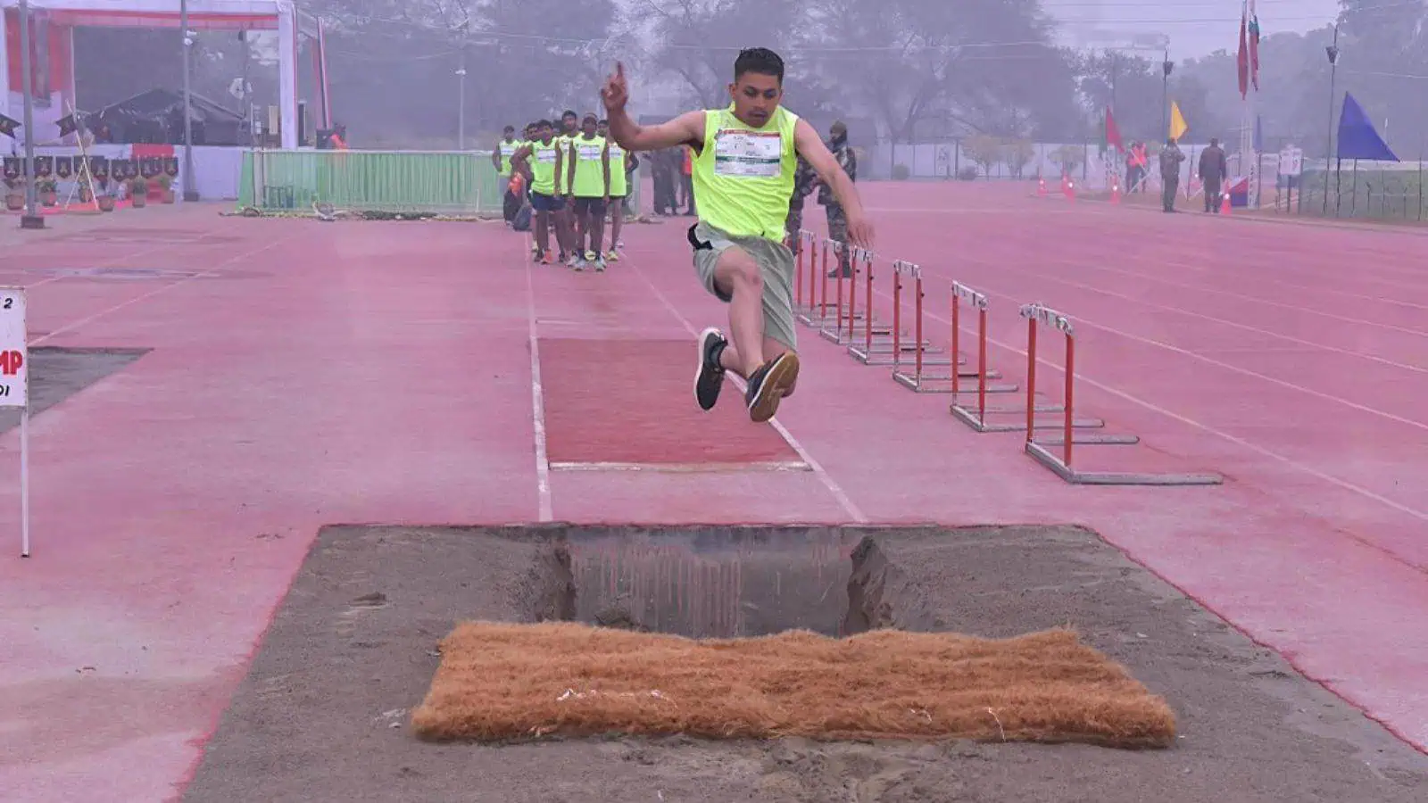 Young athlete jumping over hurdles during Indian Army Agniveer recruitment event.