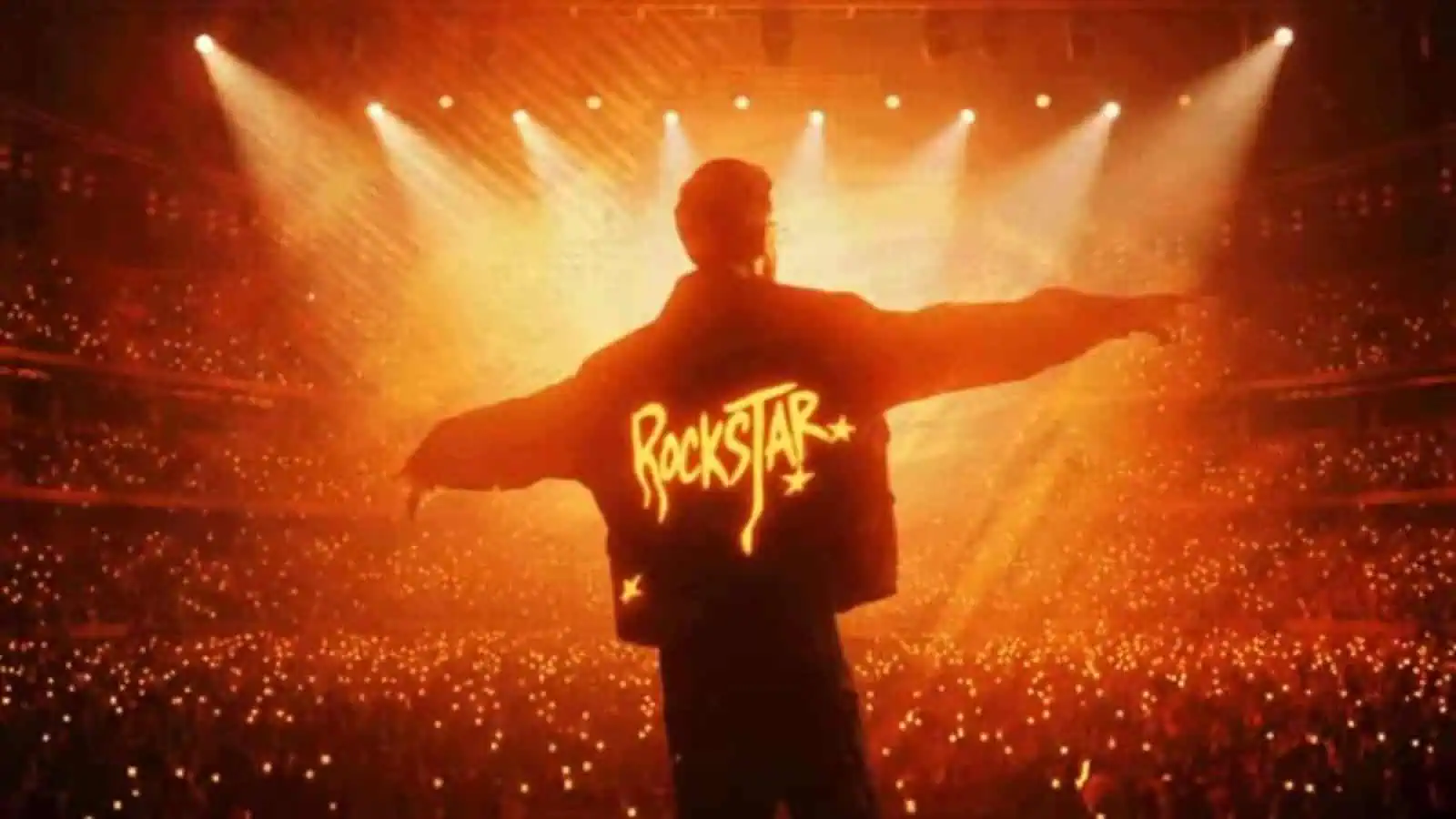 Anirudh on stage at Hyderabad concert with fans in the background.