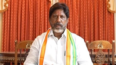 Indian politician speaking at a public event with traditional decorations.