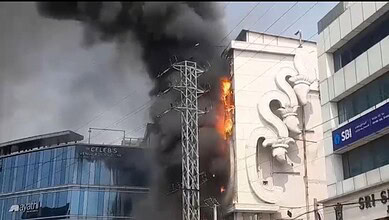 Fire at Hyderabad shopping mall with thick black smoke and flames engulfing the building.