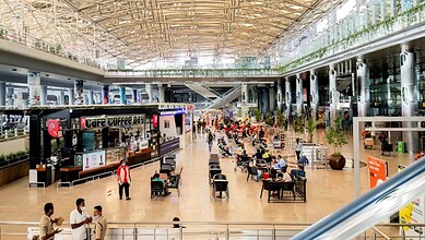 Modern Hyderabad airport terminal with passengers and cafes, showcasing Telangana's growing connectivity.