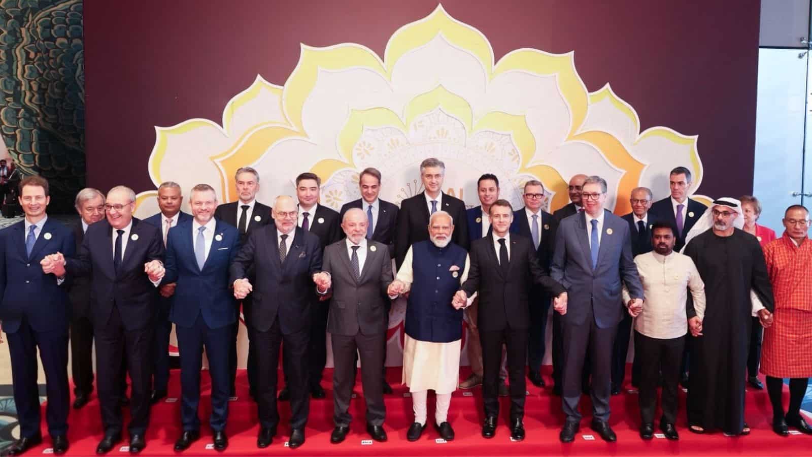 Group of international leaders and officials at the AI Impact Summit signing declaration, promoting globa.