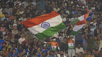 Crowd with Indian flags at cricket match amid rain concerns.