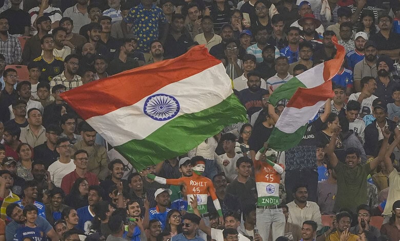 Crowd with Indian flags at cricket match amid rain concerns.