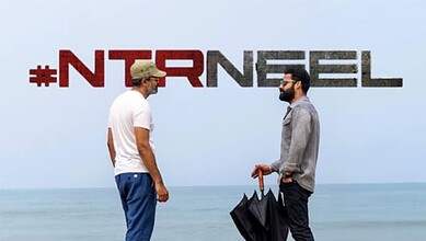 Two men talking on the beach with "#NTRNREL" text in the background.