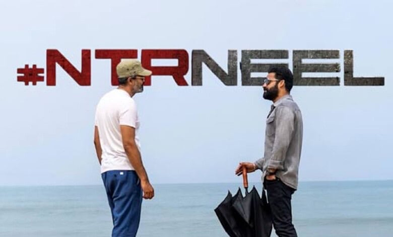 Two men talking on the beach with "#NTRNREL" text in the background.