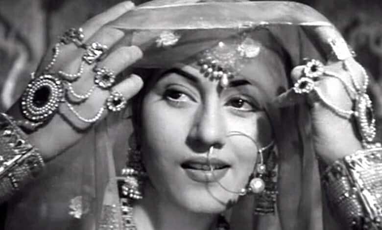 Woman in traditional Indian bridal attire with jewelry and veil, smiling softly.