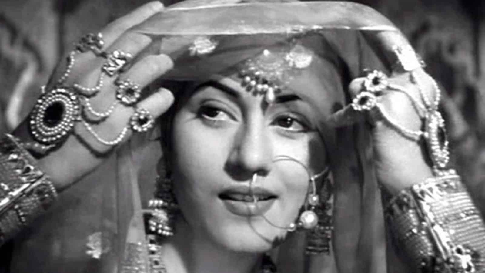Woman in traditional Indian bridal attire with jewelry and veil, smiling softly.