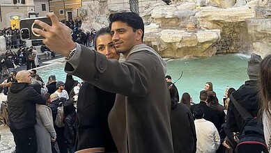 Malaika Arora taking a selfie with a man in Italy, surrounded by tourists and scenic water features.