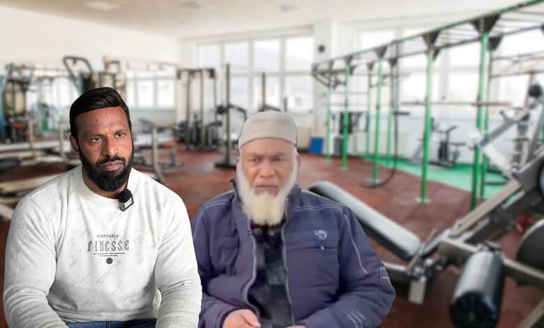 Two men in casual attire talking inside a well-equipped gym.