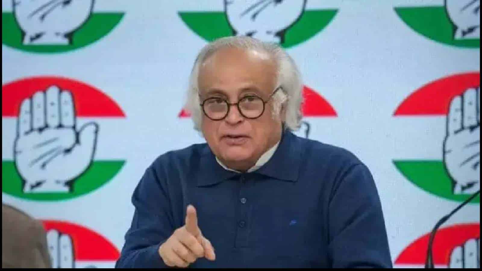 Indian Prime Minister Modi speaking at a political event with Congress symbols in the background.