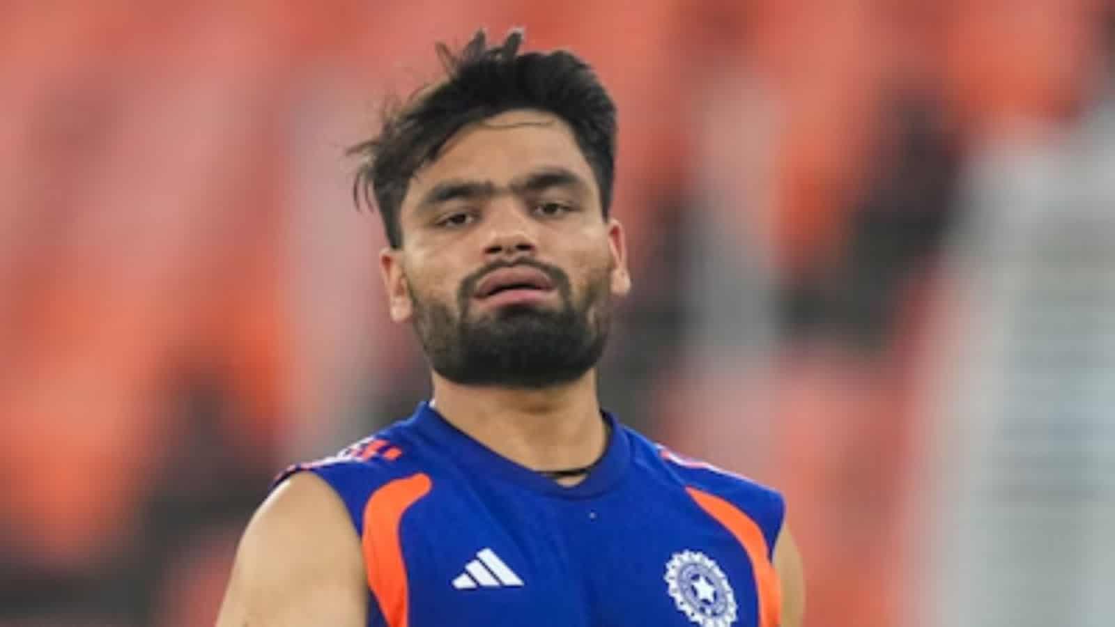 Cricket player celebrating on the field in a blue jersey with orange accents.