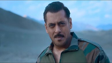 A man in military attire outdoors with mountains in the background.