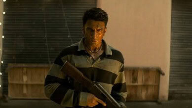 Man holding a gun in a dimly lit setting, intense expression, film scene.