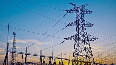 High voltage transmission tower with power lines in Telangana at sunset.