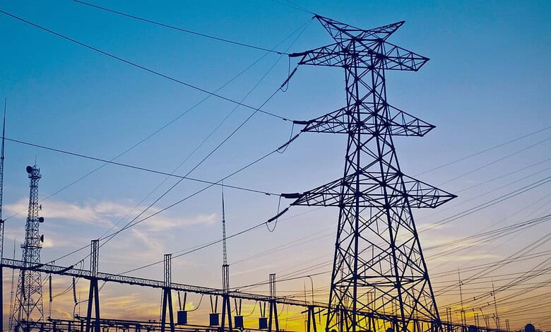 High voltage transmission tower with power lines in Telangana at sunset.
