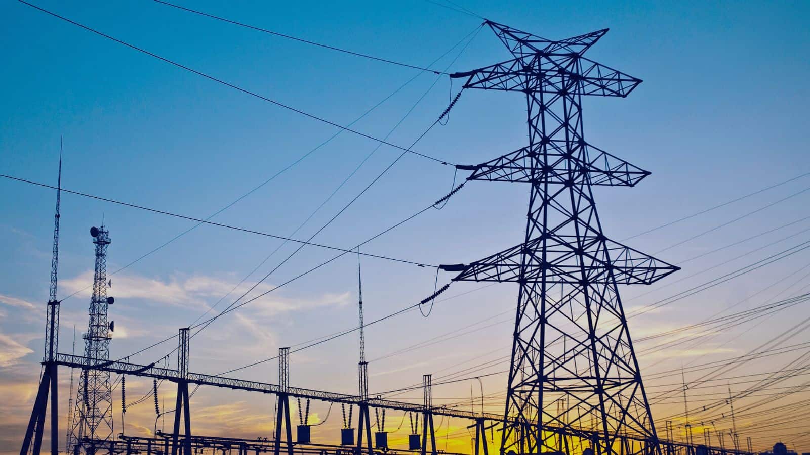 High voltage transmission tower with power lines in Telangana at sunset.