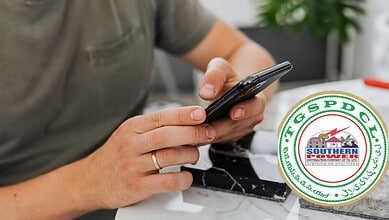 Man using smartphone with TGSPDCL (Southern Power Distribution Company of Telangana) logo overlay
