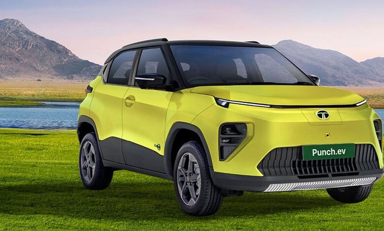 New Tata Punch EV facelift in bright yellow, parked on grass with mountains in background.