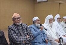 Prominent Muslim leaders participating in a discussion at a formal event in a conference room.