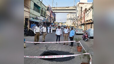 Police officers inspecting a street scene with caution tape in an urban area.