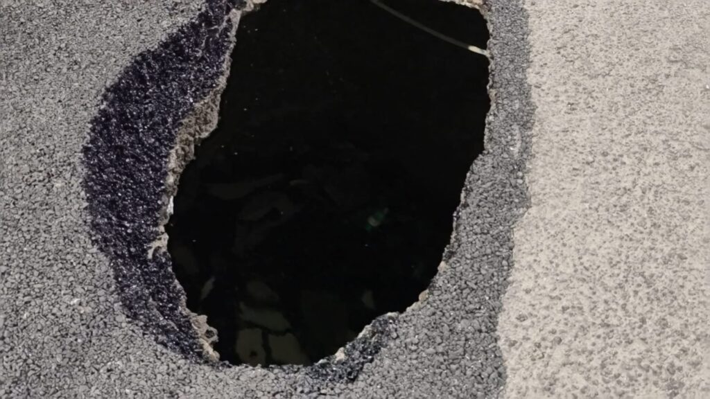 Pothole on New Malakpet Road in Hyderabad causing traffic hazards.